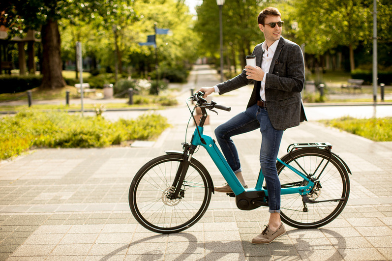 Geschäftsmann mit einem Kaffee auf einem türkisen ebike