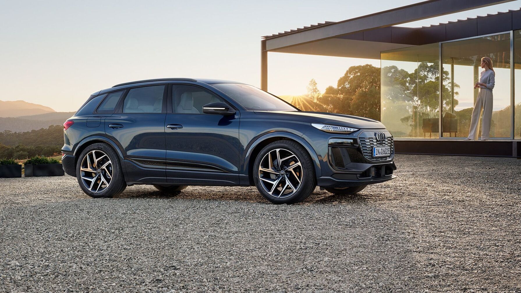 Audi Q6 SUV e-tron vor einem modernen Haus mit großer Fensterfront