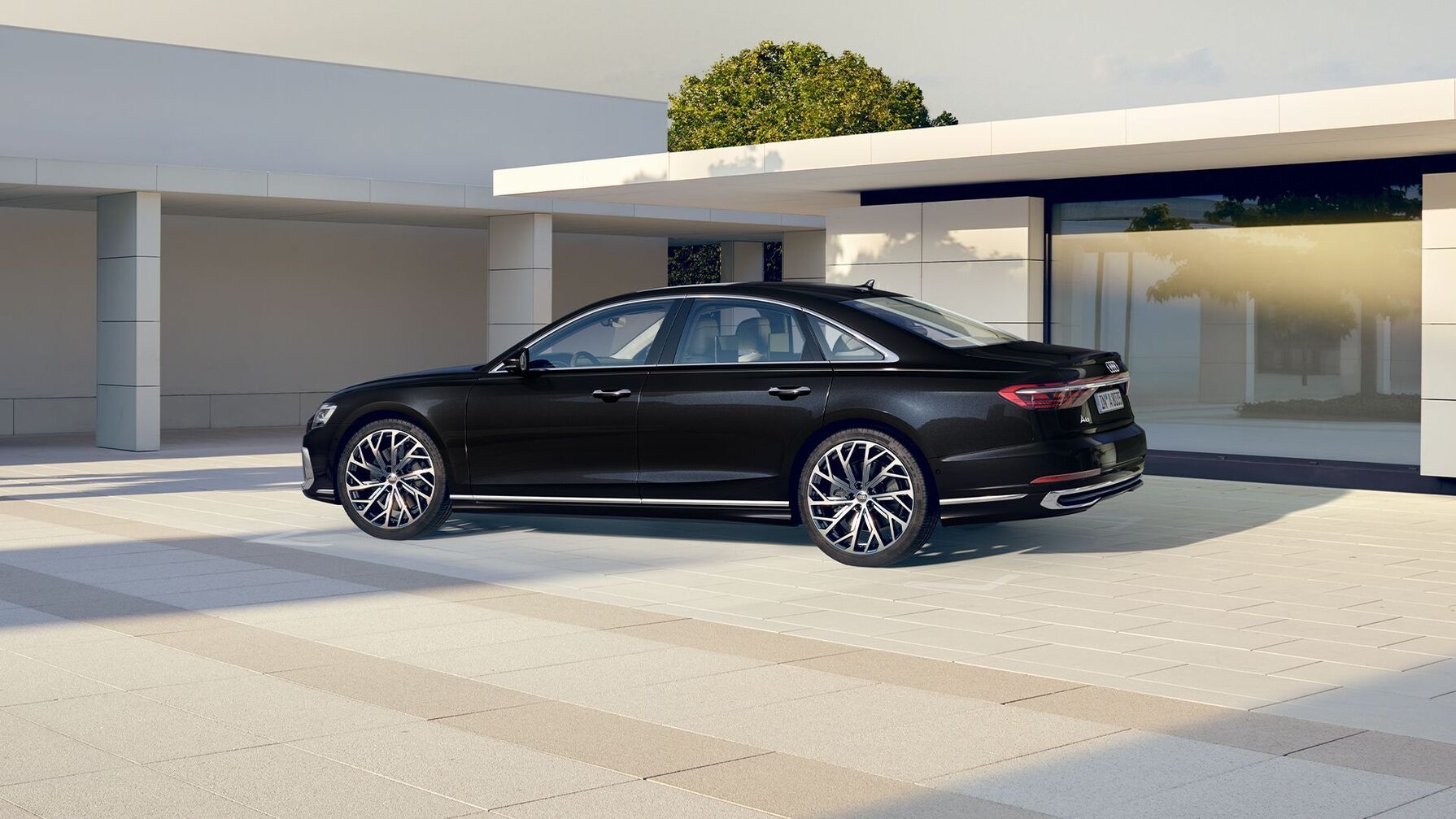 ein schwarzer Audi A8 vor einem modernen Haus mit großen Fenstern